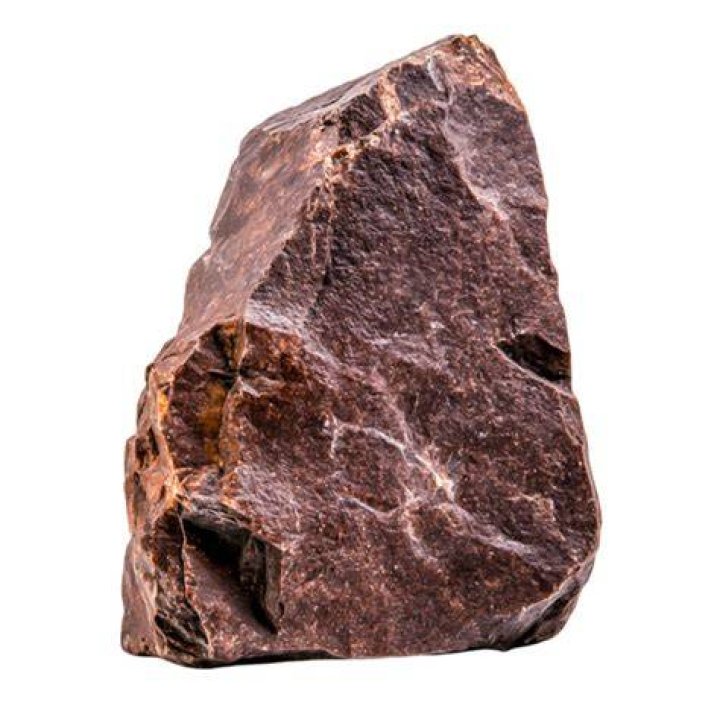 brown rock formation next to green trees with mountains in the background