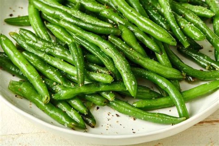 Fresh green beans in bowl on wooden table