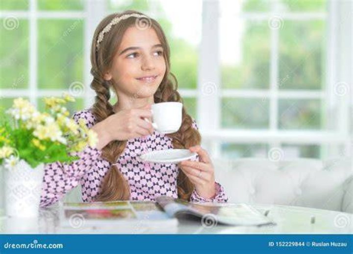 Girl drinking tea while doing work on a laptop