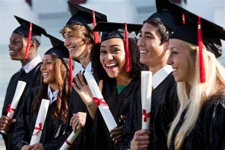 Graduating class in caps and gowns throwing caps in celebration