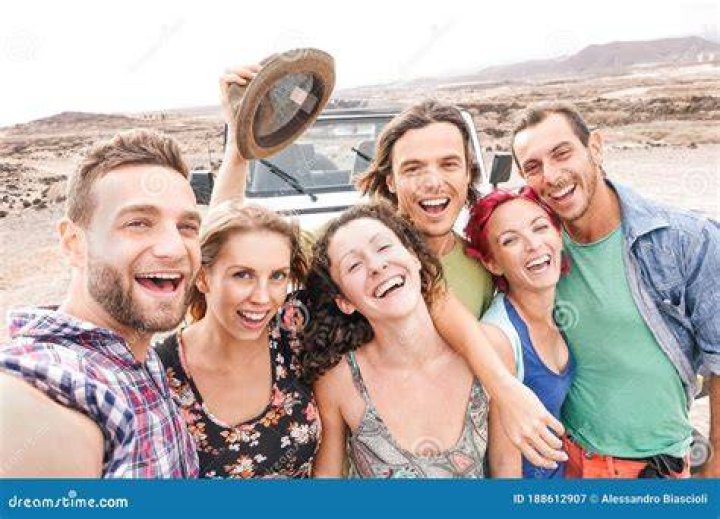 group of travel friends taking picture at sunset