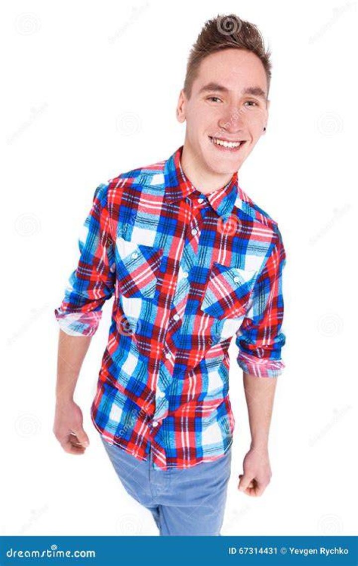 Man in checked shirt with backpack standing in front of the Taj Mahal in Agra, India.