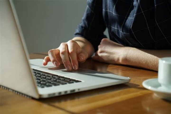 person using laptop with mug of coffee to the side