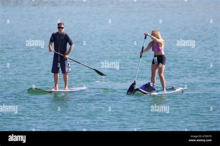 two people paddle boarding in the ocean during golden hour