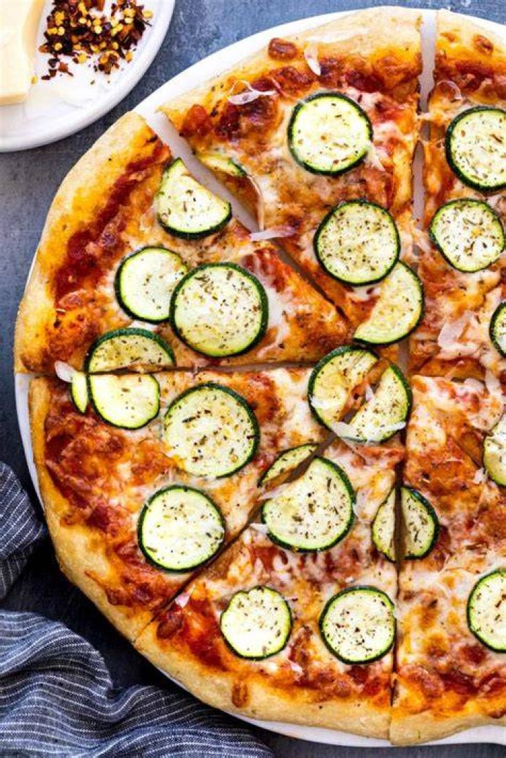 Vegatarian Pizza vegetarian pizza with zucchini, sun dried tomatoes source pesto, spinach, seeds and nuts flat lay top down composition on wooden background